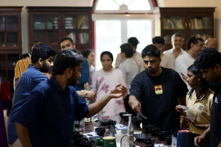 Guests gathered around a table of coffee samples and cupping bowls at Kerala Origins Kochi.
