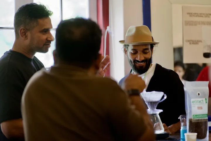 Guests beside a pour-over brewer and coffee sample bags at Cochin Club.