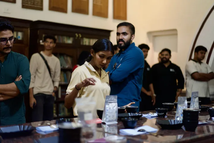 A participant discussing the coffees while guests watch across the cupping table.