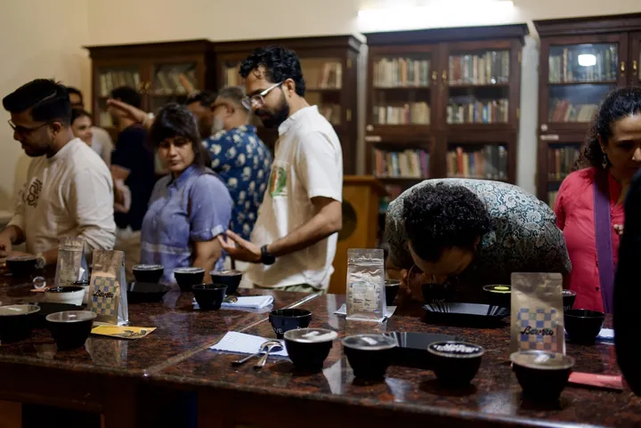 Participants exploring coffee aromas at a table lined with sample bags and cupping bowls.