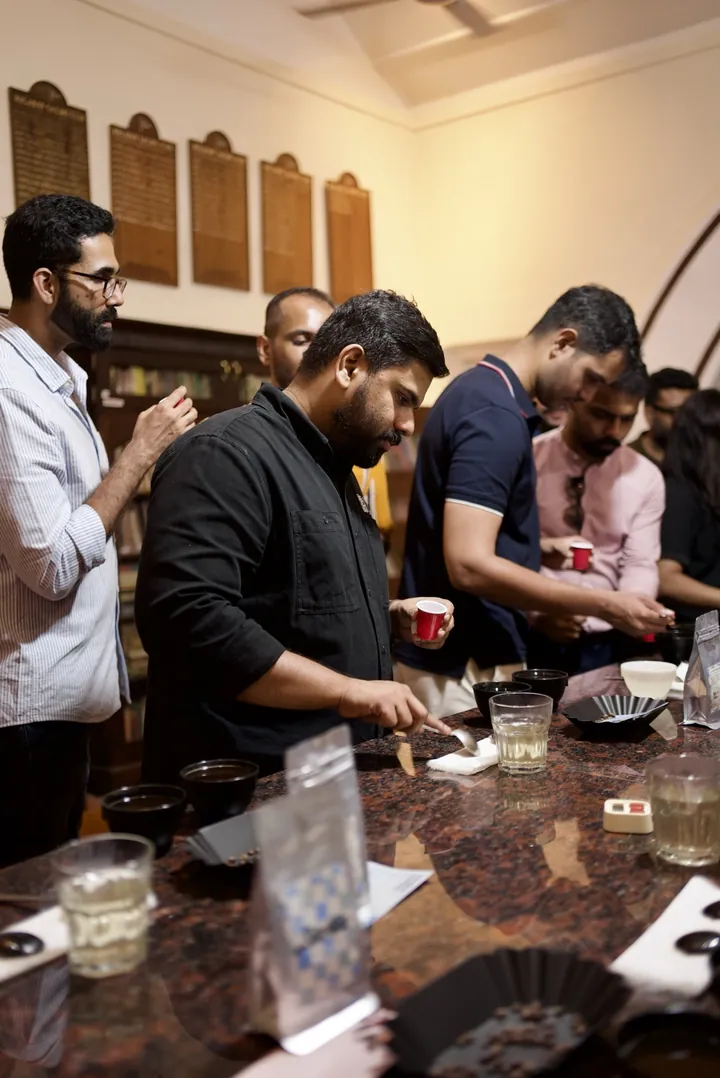 Guests holding sample cups while tasting coffees along the cupping table.