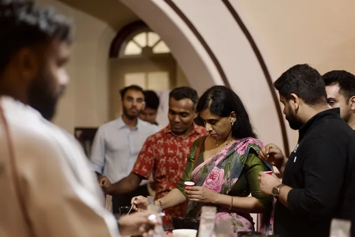 Guests tasting and discussing coffee together around the sample table.